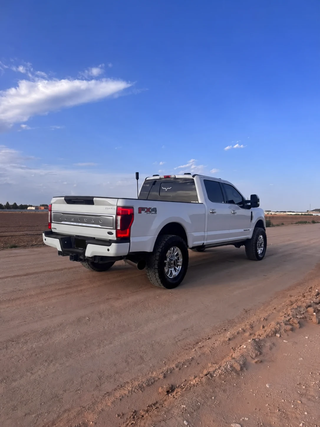 Rear three-quarter view of the white Ford F-350 on the dirt road